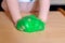 Green sticky slime in children`s hands. A little girl is playing at home with a toy called slime. The child squeezes the green sli