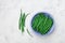 Green or string beans in blue rustic bowl on white stone table top view. Organic farm food.