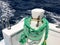 A green strong durable thick fabric ship rope, a rope for the berth, a stop attached to the ship, a boat on the background of the