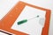 Green student gel pen on a background of orange notebook