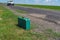 Green suitcase lonely standing  on a country roadside  at summer season