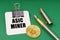On a green surface, a bitcoin coin, a pen and a sheet of paper with the inscription - Asic miner