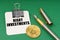 On a green surface, a bitcoin coin, a pen and a sheet of paper with the inscription - risky investments