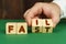 On a green surface, a man puts cubes with the inscription - FAIL ,FAST