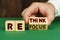 On a green surface, a man puts cubes with the inscription - rethink, refocus