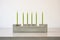 green taper candles in a modern concrete holder