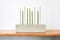 green taper candles in a modern concrete holder