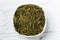 Green tea leaves bancha in white bowl on wooden background.