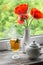 Green tea with lemon and mint in a glass mug and poppies in a white vase