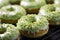 Green tea matcha doughnuts covered with green matcha powder glaze and grated pistachio on a cooling rack, matcha dessert close-up