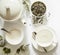 Green tea - tea leaves, empty teacup, teapot, sugar bowl on a white background, top view