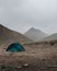 Green tent in the Himalayan mountains on a foggy day
