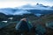 Green tent in the mountains during a colorful sunset. Night bivouac, million star hotel under night sky, tent on pass in Alps.