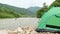 Green tent on the rocky bank of a mountain river, Yukon Tributary, Klondike, Canada.