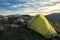 Green tent on rocky peak of Nebrodi Park, on background snowy Etna Mount and cloudscape