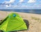 Green tent on the sea sand. Hiking tent on the beach. Baltic coast quiet sea