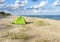 Green tent on the sea sand. Hiking tent on the beach. Baltic coast quiet sea