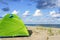 Green tent on the sea sand. Hiking tent on the beach. Baltic coast quiet sea