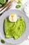 Green thin pancakes with spinach, poached egg, sour cream, lemon