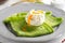 Green thin pancakes with spinach, poached egg, sour cream, lemon