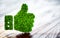 Green thumbs up sign on blurred wooden background.