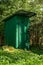 Green timber frame outhouse in greenery.