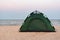 Green tourist tent on the sandy beach. Camping by the sea