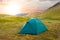 Green touristic tent in a mountain  valley at the sunset