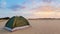 Green touristic tent in a sandy desert at the sunset