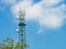 Green tower with microwave link and TV transmitter antennas, telecommunication mast antennas wireless technology over blue sky