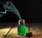 Green toxic water with smoke in magic bottle on black and wooden background. Selective focus
