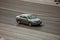 Green Toyota Camry cruising the highway. Aerial view of shiny car moving on the city road