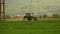 Green tractor plowing cereal field between mountains