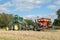 A green tractor with a seed drill in a stubble field