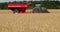 A green tractor trailer with a red grain tank riding in the field. Prores, slow motion