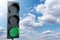 Green traffic light on a background of blue sky. Symbol of sustainable energy and development