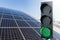 Green traffic light on a background of solar panels. Symbol of sustainable energy and development