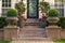 Green trees cover vintage home facade with stone flower vases and hanging lights