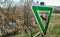 Green triangular sign with the picture of a bald eagle and the German inscription Nature reserve in front of a pond with a meadow