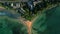 Green tropical rocky island in the middle of blue-green sea washed by waves aerial descending shot. Parrot Rock in