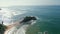 Green tropical rocky island in the middle of blue-green sea washed by waves aerial view. Parrot Rock in Mirissa, Sri