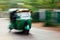 A green tuktuk rickshaw zooms through the street in Anuradhapu