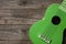 Green ukulele on a wooden table, copy space