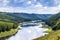 Green valley in summer with forests on hills and big river below