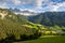 Green valley of Val di Funes at foot of rocky Italian Dolomites with rustic houses