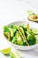 Green vegan tacos with broccoli, avocado and green flat bread in white bowl, white marble background. Vegetarian fast food