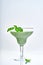 Green vegetable juice or smoothie garnished with leaf of fresh basil in coctail margarita glass isolated on white