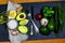 Green vegetables avocados, pepper, lemon, ginger, garlic, oil, sea salt, rucola salad, cucumber, fork and knife on a shale board,