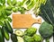 Green vegetables and herbs assortment around wooden cooking board.