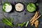 Green vegetables raw snack board with various dips. Yogurt sauce or labneh, hummus, herb hummus or pesto with crackers, grissini